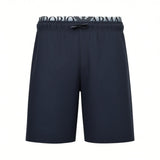 Navy blue beachwear shorts with a white elastic waistband featuring black 'EMPORIO ARMANI' text and a black drawstring.