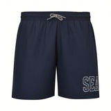 Navy blue swim shorts with an elastic waist, black and white braided drawstring, and "SEA" in white outlined letters on the r