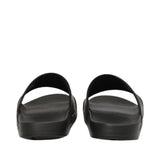 Pair of black slide sandals with wide single straps and contoured soles, viewed from the back.