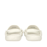 Pair of off-white rubber slide slippers with wide top straps, textured footbeds, and embossed eagle logos on the outer heels.