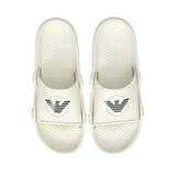 Off-white molded slide slippers with black circular eagle logos on the straps and textured footbeds.