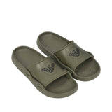Pair of olive green beachwear slide slippers with a wide strap, featuring a black logo on each strap and a textured footbed.