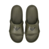 Pair of olive green rubber slides with wide straps, each featuring a dark grey eagle logo. Textured footbeds with "EMPORIO AR