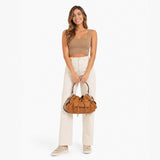 Woman holding a brown handbag against a white background.