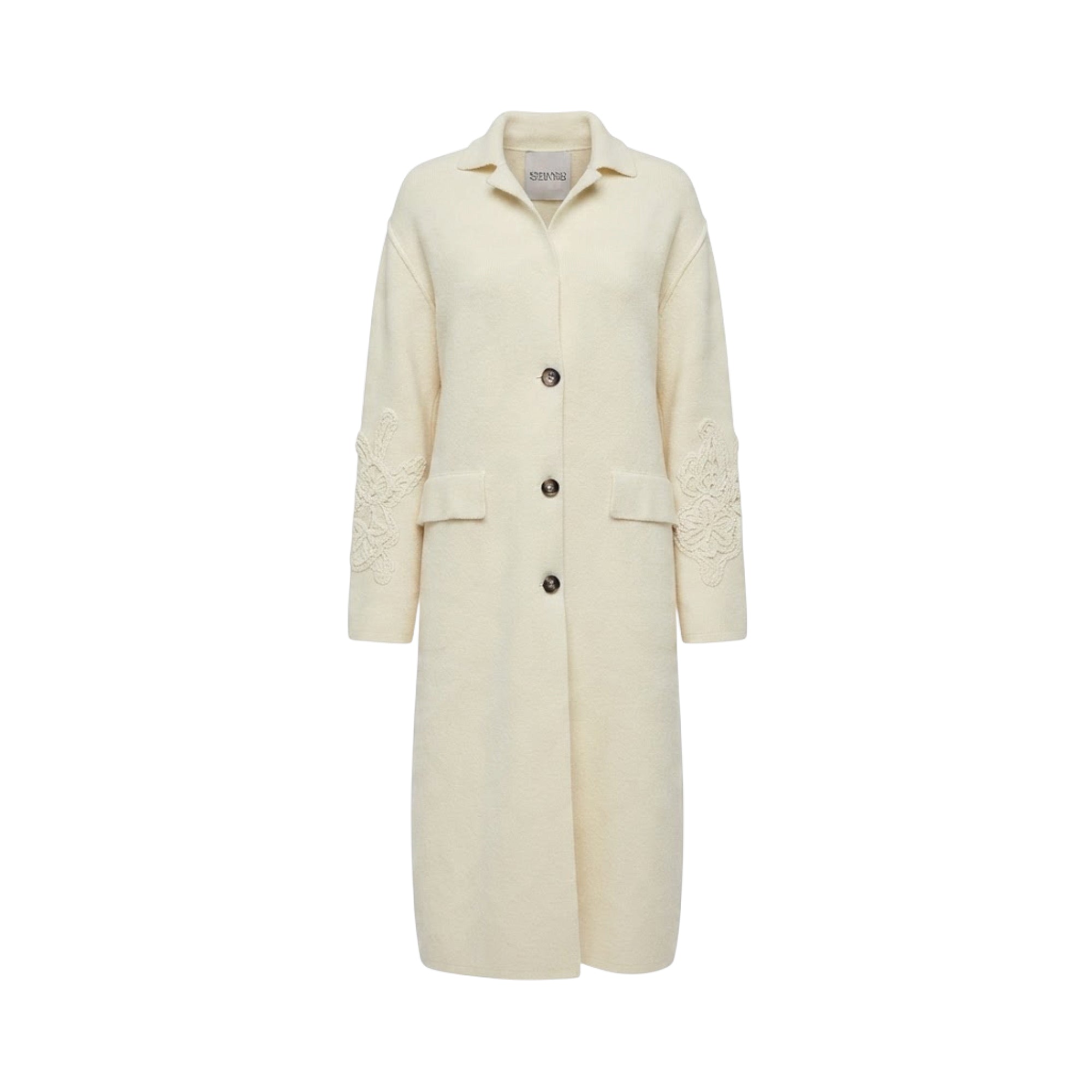 Beige longline knit coat with a collar, three front buttons, two patch pockets, and intricate floral embroidery on both sleev