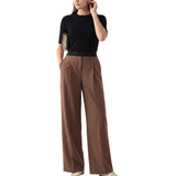 A woman modeling a black short-sleeve knit top and high-waisted brown wide-leg trousers, holding a small metallic clutch against a plain white background.