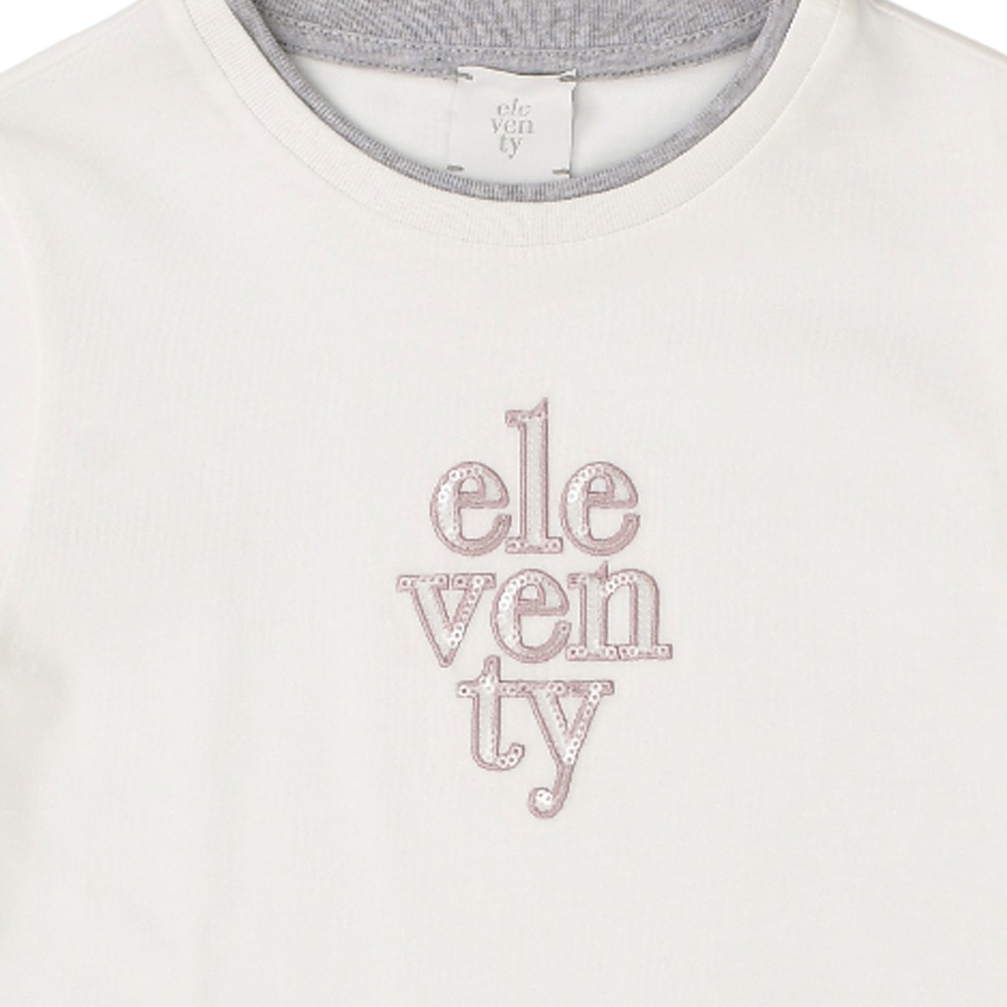 Ivory crew neck t-shirt with a grey inner neck trim. "eleventy" graphic on front, with "ven" in pink sequins and "ele" and "t