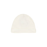 Front view of a soft off-white cotton jersey baby beanie hat featuring a turned-up brim and a small embroidered interlocking logo in the center.