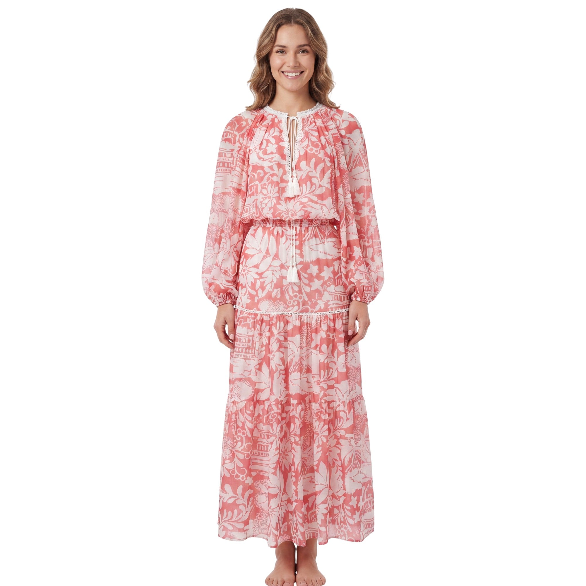 Full-length front view of a smiling model wearing the Ermanno Firenze coral pink and cream floral maxi dress with tassel neck ties from BLUE SALON shop.