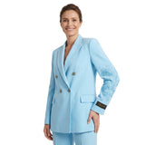 Woman wearing a light blue suit with embroidered details on a white background.