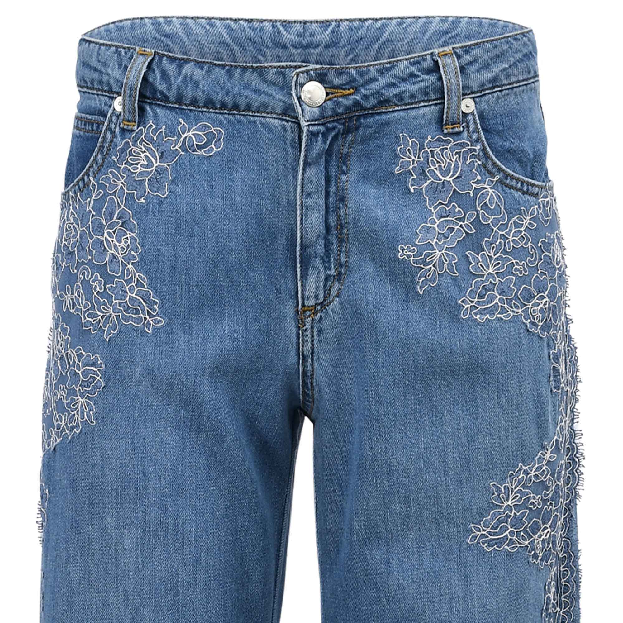 Close-up front view of the Ermanno Firenze jeans showcasing the silver-tone metal hardware, button closure, and intricate white botanical lace overlays from BLUE SALON shop.