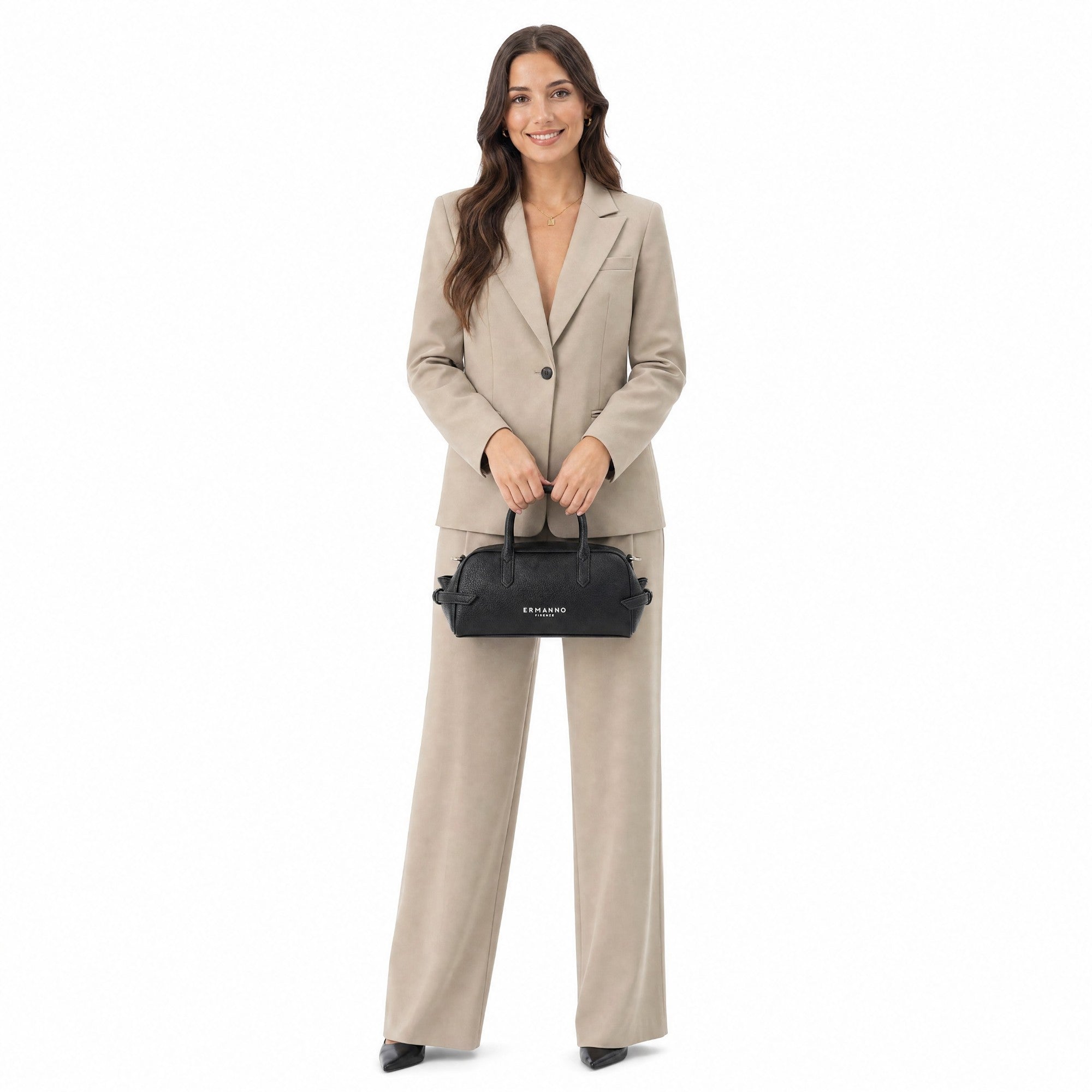Woman in a beige suit holding a black handbag on a white background.