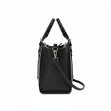 Side profile view of the black Ermanno Firenze tote bag at BLUE SALON, showcasing the depth, side perforated patterns, and silver hardware attachment for the shoulder strap.