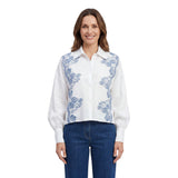 Front view of a smiling model wearing the Ermanno Firenze white blouse with blue lace details, styled with dark blue jeans from BLUE SALON shop.