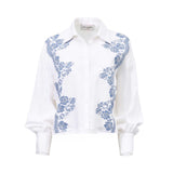 Front view of an Ermanno Firenze white blouse featuring blue floral lace applique along the front panels and balloon sleeves from BLUE SALON shop.