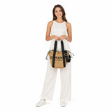 Full-length model image showcasing a woman in an all-white summer outfit holding the Ermanno Firenze raffia tote bag from the BLUE SALON shop to demonstrate its size and scale.