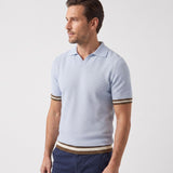 Light blue knit polo sweater with short sleeves, V-neck collar, and ribbed cuffs and hem featuring brown and white stripes.