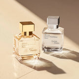 Clear rectangular glass perfume bottle with a silver-toned square cap and a white label.