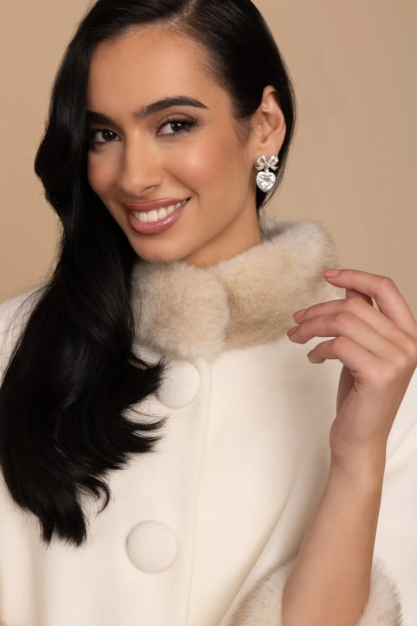 Silver-toned earring with a crystal-encrusted bow and a large, faceted clear heart crystal.