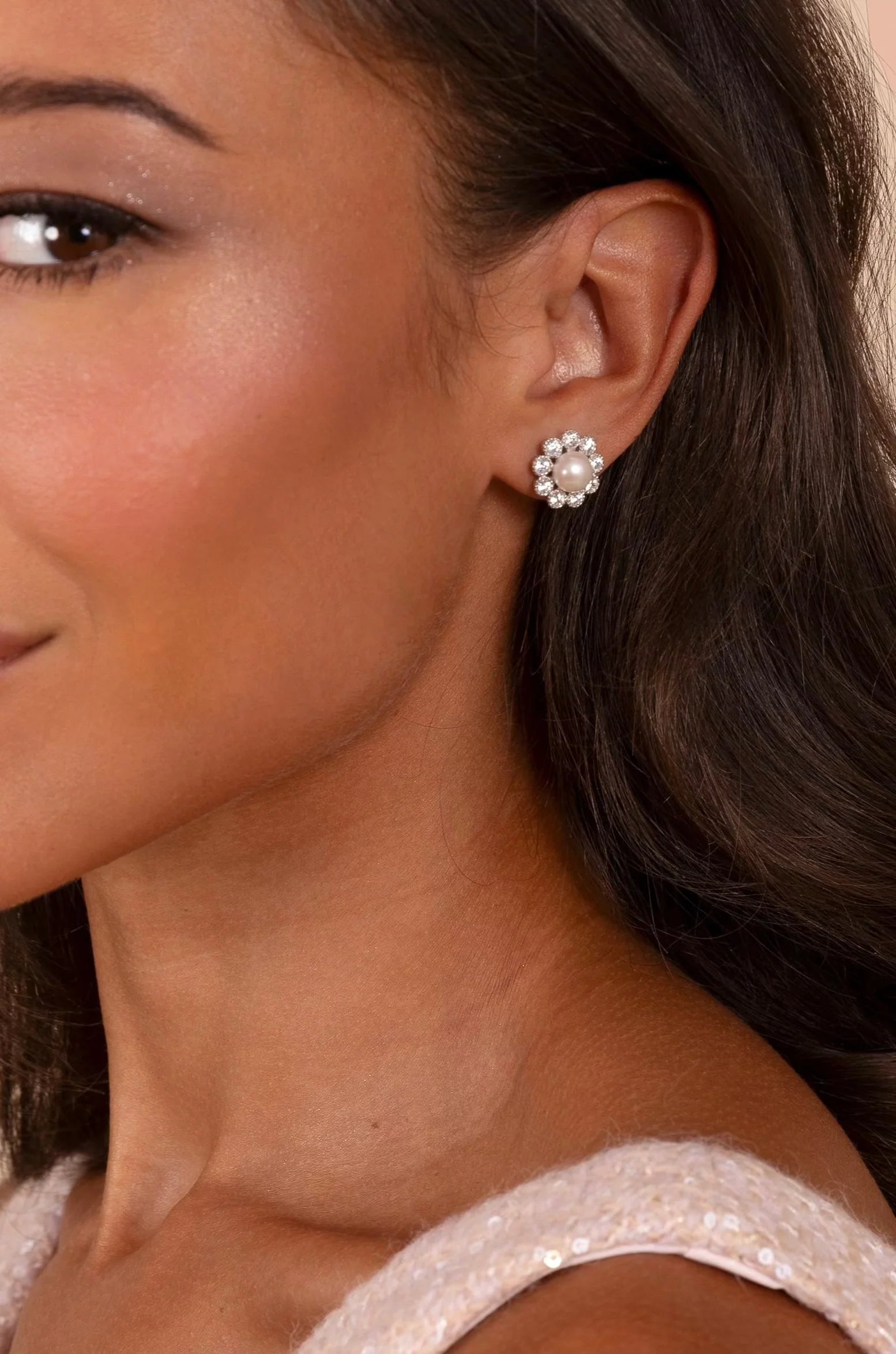 One silver-toned stud earring with a light pinkish-cream pearl center, surrounded by a halo of clear stones.