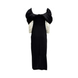 Fiordelli Donna black evening gown featuring a voluminous off-the-shoulder neckline, draped wrap skirt, and ivory long sleeves covered in sparkling crystals.