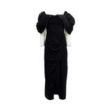 Fiordelli Donna black evening gown featuring a voluminous off-the-shoulder neckline, draped wrap skirt, and ivory long sleeves covered in sparkling crystals.