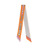 Flat view of the Muni women’s orange printed twilly scarf, with belt buckle motif and brown polka dot detailing. Available for Online Purchase
