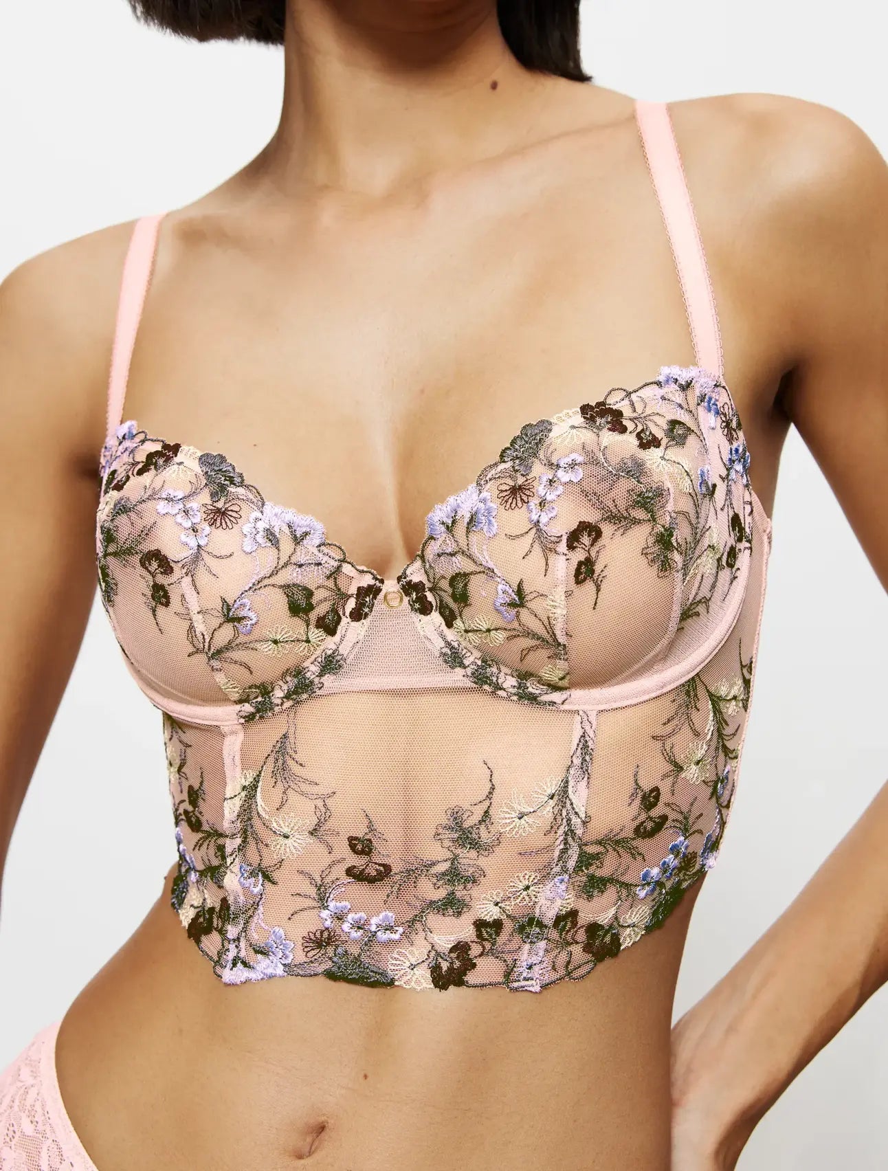 Front view of model wearing the Triumph Sensual Spotlight light pink corset, showcasing the intricate lace panels and structured waist design. Now Available Online