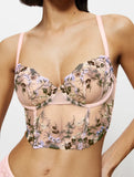Front view of model wearing the Triumph Sensual Spotlight light pink corset, showcasing the intricate lace panels and structured waist design. Now Available Online
