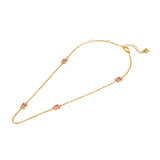A full-length studio product presentation of the Escada Florence station necklace, displaying the gold-plated cable chain adorned with four evenly spaced pink enamel monogram links and the adjustable clasp assembly.
