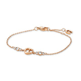 A high-resolution studio display of the Aigner Iva women's rose gold-plated stainless steel bracelet, showing the central horseshoe motif, clear crystal clusters, thin cable chain, lobster clasp, and small logo charm.