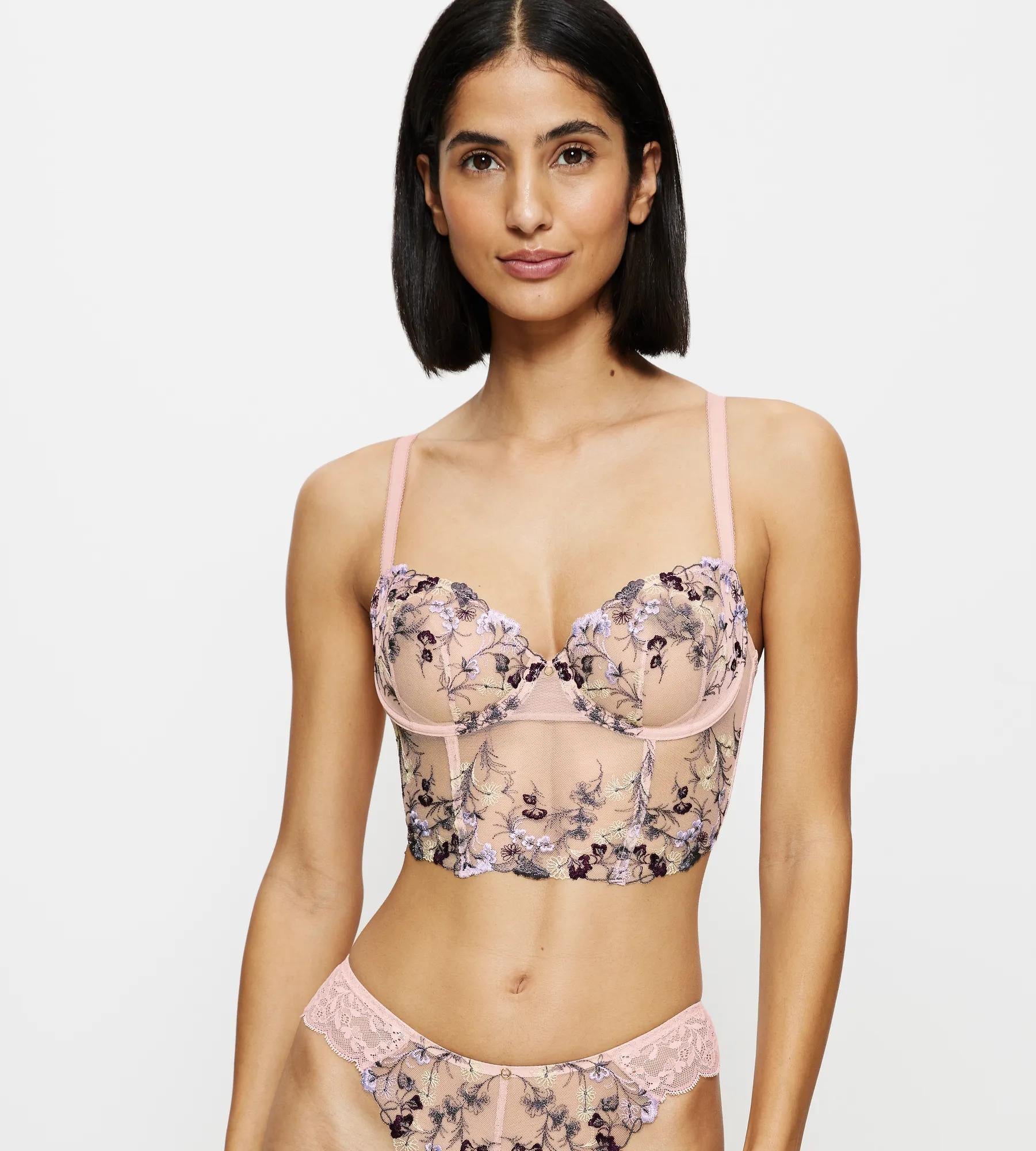 Full front view of model wearing the Triumph Sensual Spotlight light pink corset, showcasing the intricate lace panels and structured waist design. Now Available Online