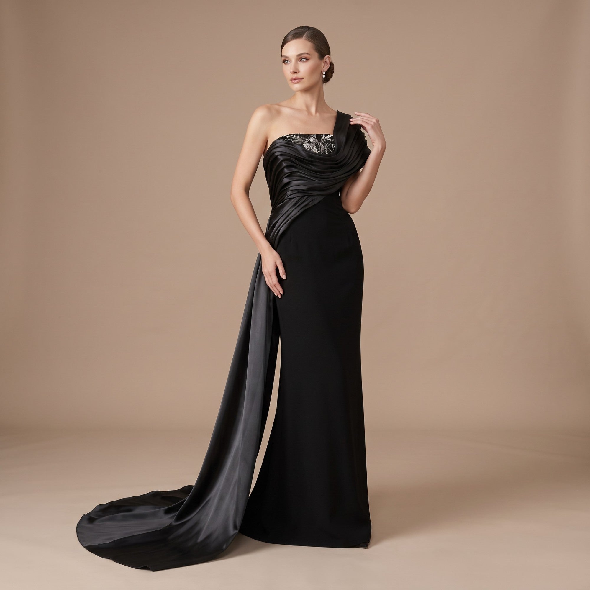 Black one-shoulder gown with a draped bodice, silver-toned embellishment, and a long flowing train.