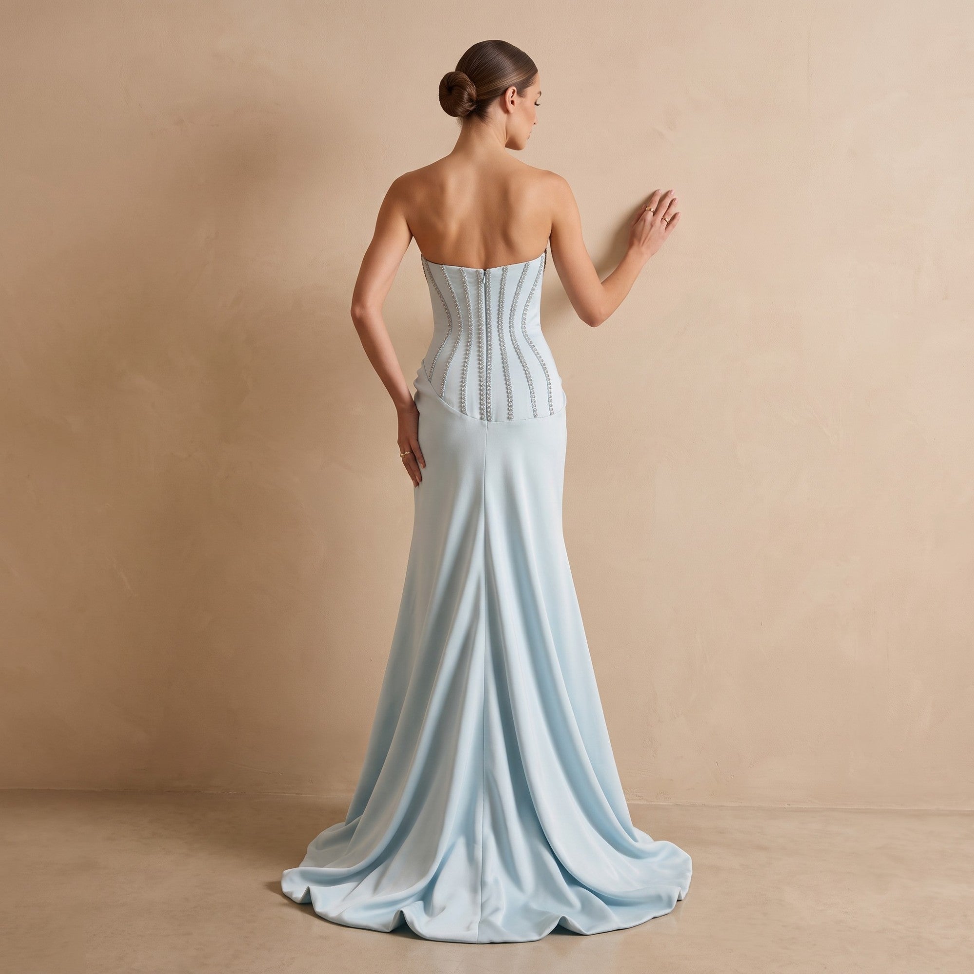 Light blue strapless gown with a fitted bodice featuring vertical silver-toned embellishments on the back, and a flowing merm