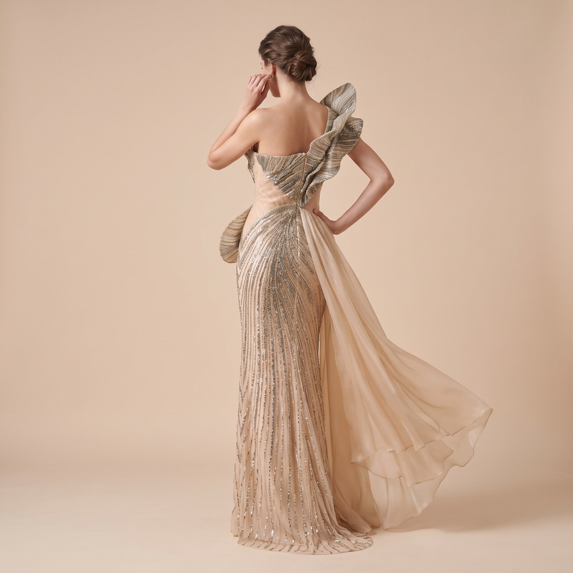 Nude one-shoulder gown with a ruffled shoulder and silver-toned beaded embellishments. Features a draped hip detail and a she