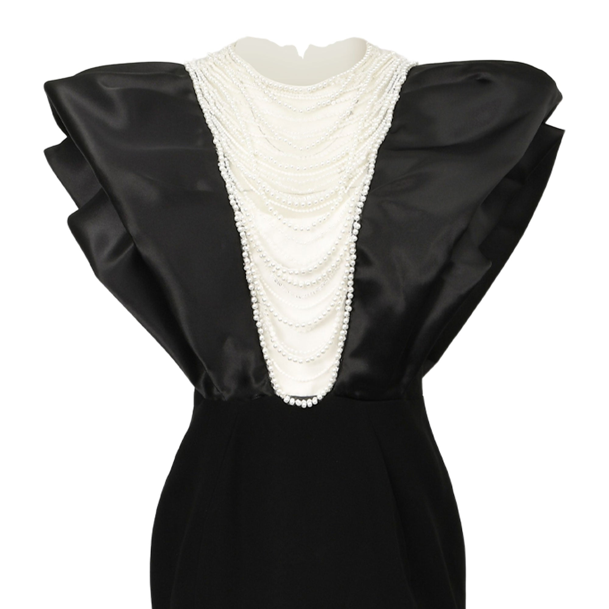 Black and white dress with a black satin top, voluminous cap sleeves, and a white V-neck with cascading pearls. Fitted black