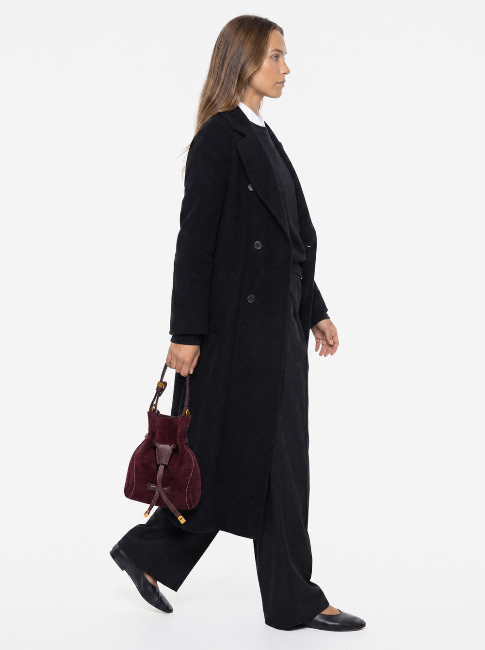 Burgundy suede drawstring bucket bag with smooth leather-like vertical strap, white stitching, and gold-toned hardware.