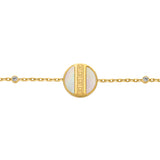 Gold-toned chain bracelet with a circular mother-of-pearl charm and a gold-toned Greek key pattern. Small clear crystals on t