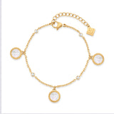 Gold-toned chain bracelet with three round mother-of-pearl charms featuring a Greek key border, and four small clear gemstone