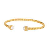 Gold-toned twisted open-cuff bangle with white faux pearls, clear crystals, and a Greek key pattern on the end caps.