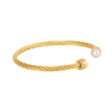 Gold-toned twisted cuff bracelet with a white pearl on one end and a gold-toned cap with crystals on the other. Both ends hav
