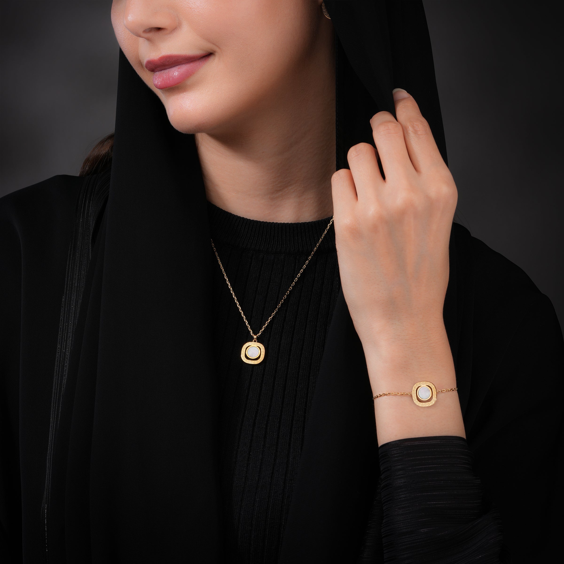 Gold-toned necklace and bracelet set. Each features a square pendant/charm with rounded corners, a textured edge, and a white