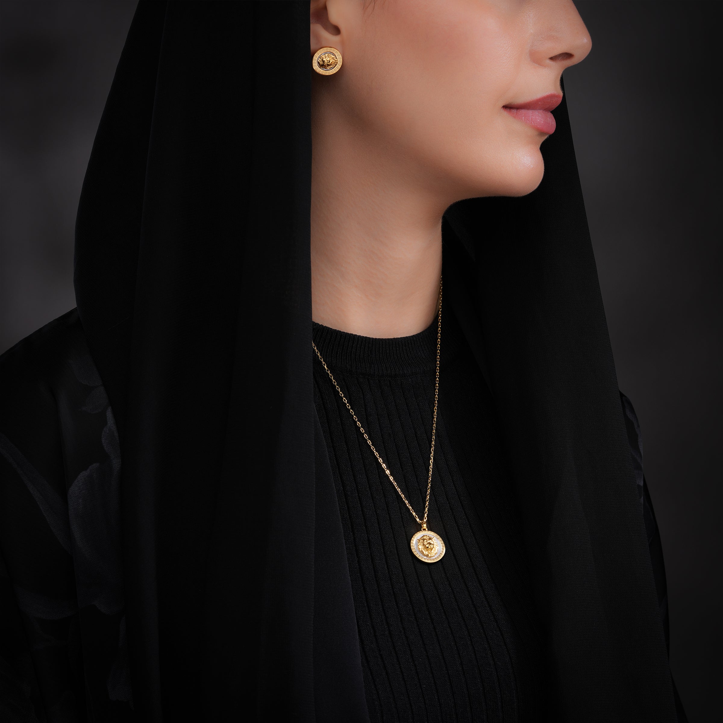 Gold-toned round stud earrings with lion head on white mother-of-pearl. Matching necklace has a pendant with lion head and cl