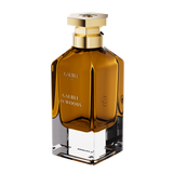 A three-quarter perspective view of the Galbee Paris Galbee Is Woody perfume bottle, showing its clear glass base, amber interior, and hexagonal gold cap.