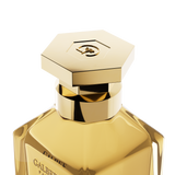 A close-up view of the golden hexagonal cap of the Galbee Paris perfume bottle, highlighting the intricate bee motif engraved on top.