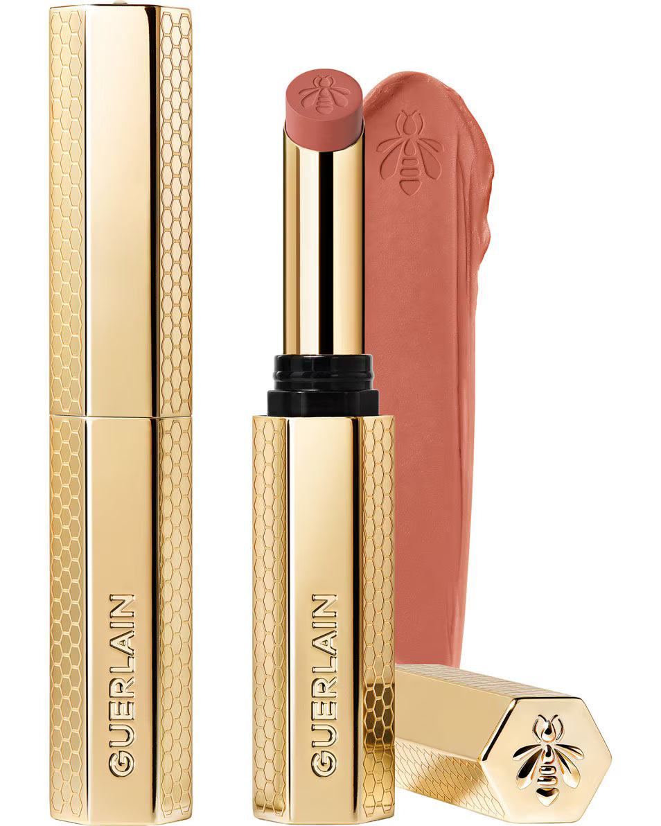 Guerlain KissKiss Honey-Infused Intense Lipstick in its slim, refillable golden honeycomb case, shown next to a rich red lipstick bullet and texture smudge, available at blue salon.