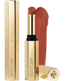 Guerlain KissKiss Honey-Infused Matte Lipstick in its signature slim golden honeycomb case, shown with an open deep burgundy-brown lipstick bullet and a velvety color smudge texture, available at blue salon.