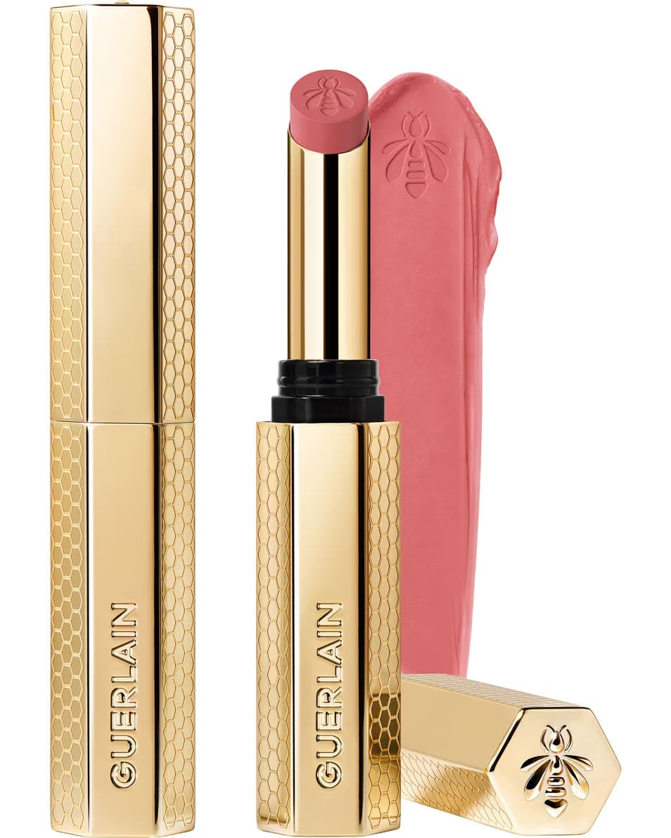 Guerlain KissKiss Honey-Infused Matte Lipstick in its signature slim golden honeycomb case, alongside an open vivid raspberry-pink lipstick bullet and smooth texture smudge, available at blue salon.