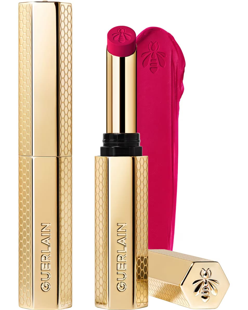 Guerlain KissKiss Honey-Infused Matte Lipstick in its signature slim golden honeycomb case, alongside an open vivid raspberry-pink lipstick bullet and smooth texture smudge, available at blue salon.