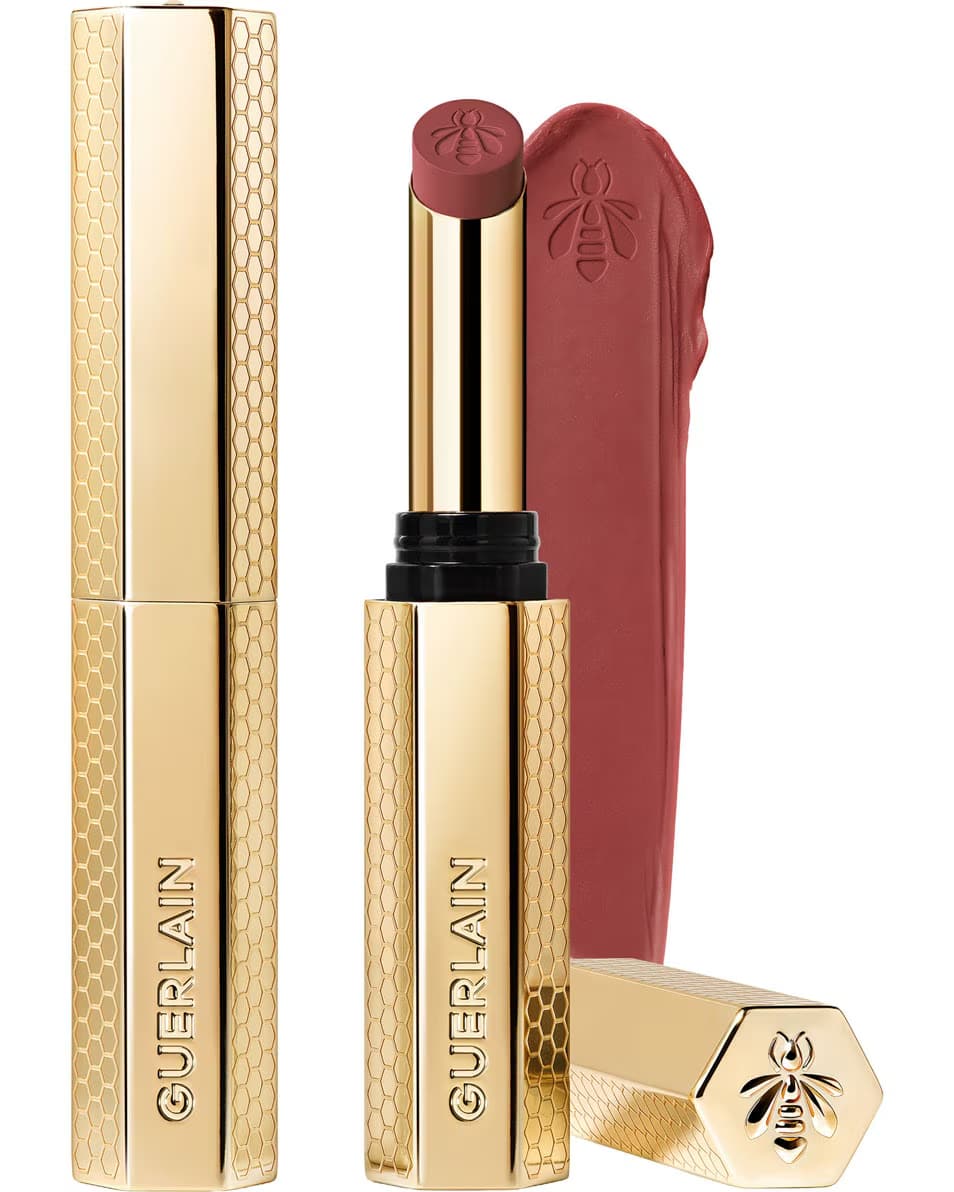 Guerlain KissKiss Honey-Infused Matte Lipstick in its signature slim golden honeycomb tube, featuring an open deep plum-berry lipstick bullet next to a velvety color smudge, available at blue salon.